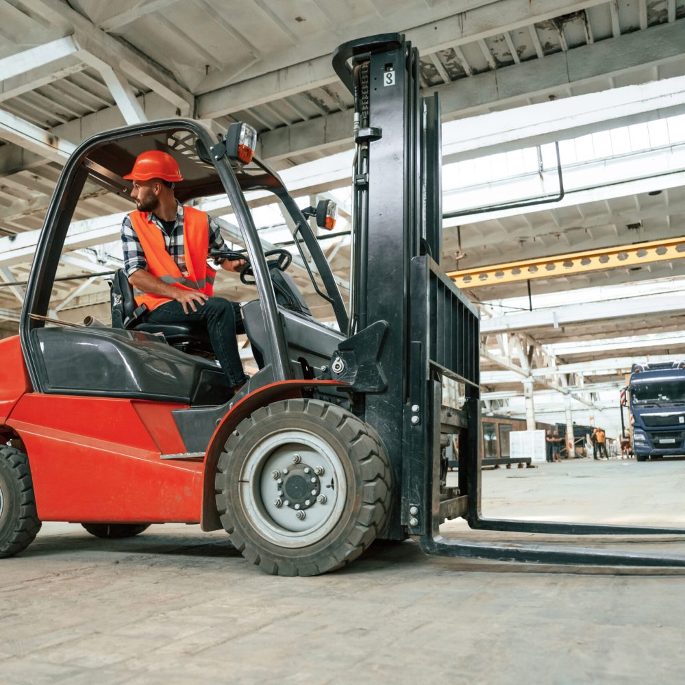 Driving the forklift. Industrial worker in wooden warehouse.
